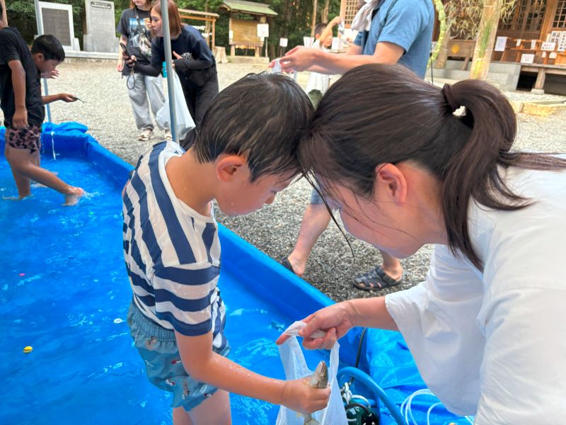 鮎をビニール袋に入れる親子