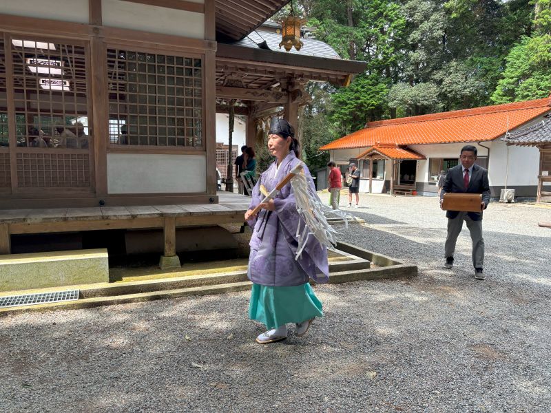 拝殿を出て山の方へ移動する女性宮司