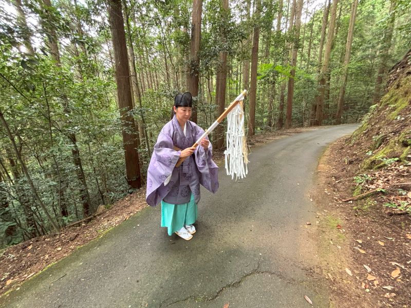 焚き上げた人形の前で祈りを捧げる女性宮司