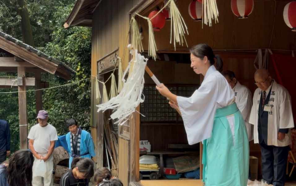 餅まきをする女性宮司