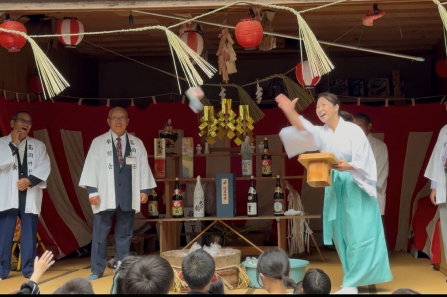 餅まきをする女性宮司