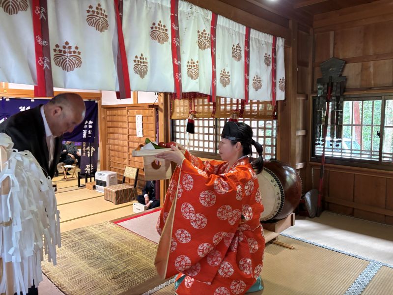 春祭りでお供え物を受け取る女性宮司