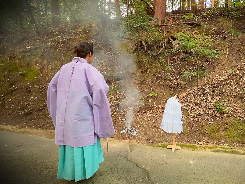 焚き上げた人形に祈りを捧げる女性宮司